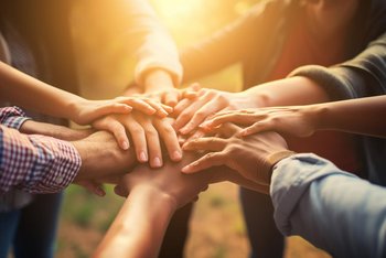 portrays a diverse group of volunteers joining hands in unity